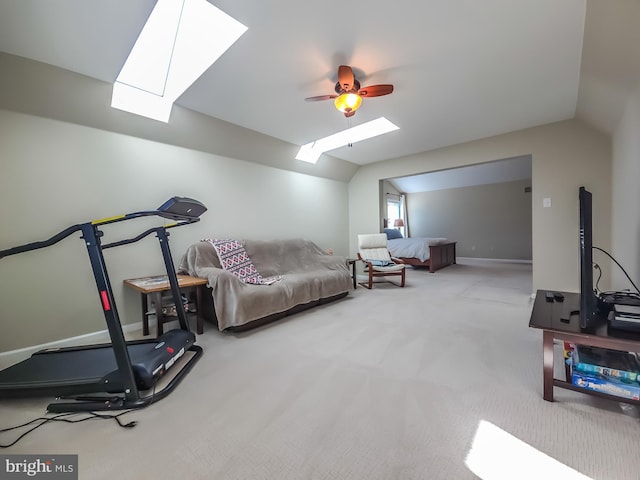 exercise area with carpet flooring, vaulted ceiling with skylight, and ceiling fan