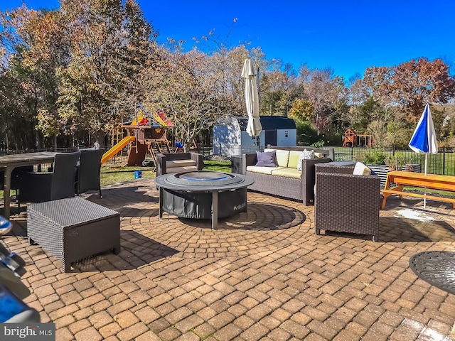 view of patio with a playground and an outdoor living space with a fire pit