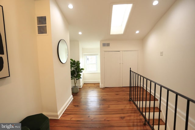 corridor with dark hardwood / wood-style flooring and a skylight