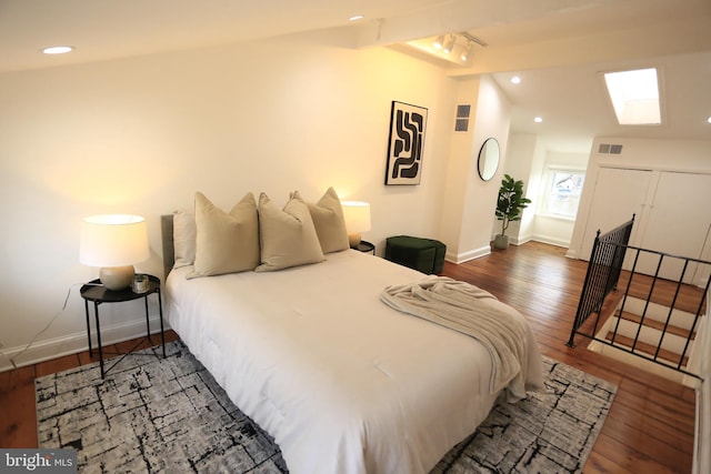 bedroom featuring dark wood-type flooring, beam ceiling, and a skylight