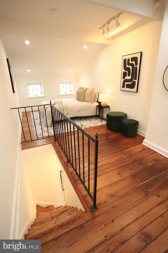 staircase with hardwood / wood-style floors and rail lighting