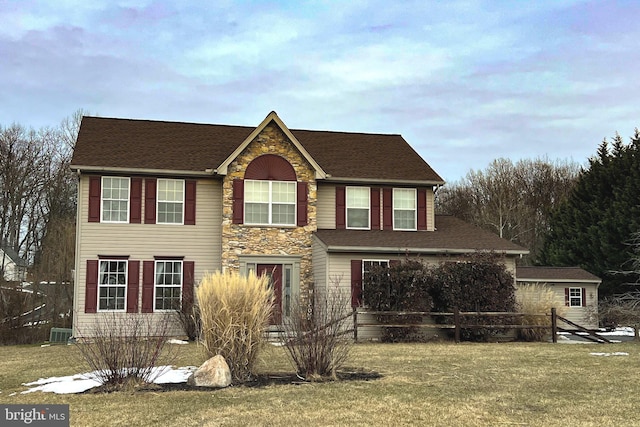 view of front facade with stone siding, central AC, and a front lawn