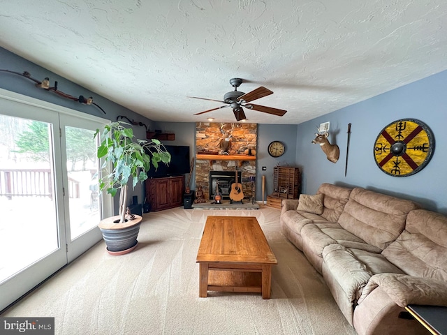 living room featuring a textured ceiling, ceiling fan, light carpet, and a fireplace