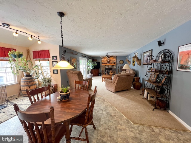 dining area with light carpet, vaulted ceiling, a textured ceiling, and a stone fireplace