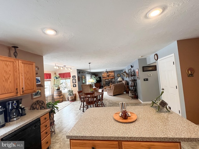 kitchen with a center island, black dishwasher, light countertops, and a textured ceiling