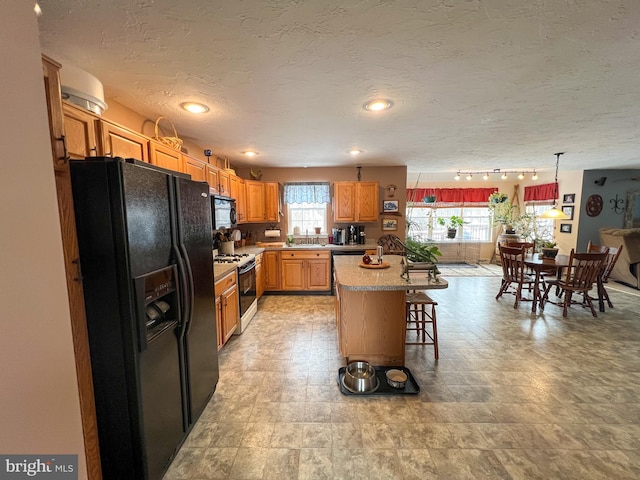 kitchen with a kitchen bar, light countertops, a healthy amount of sunlight, and black appliances