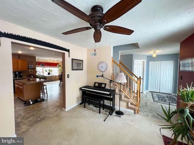 interior space with carpet floors, visible vents, a textured ceiling, baseboards, and stairs