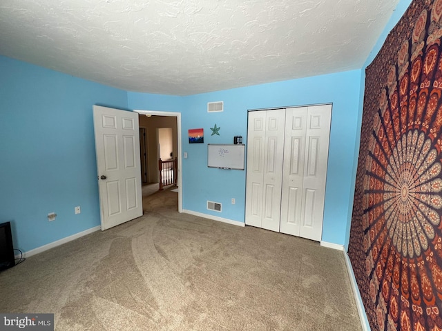 unfurnished bedroom with carpet, visible vents, a textured ceiling, and baseboards