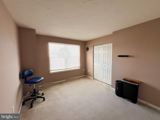 miscellaneous room featuring a textured ceiling, carpet floors, visible vents, and baseboards