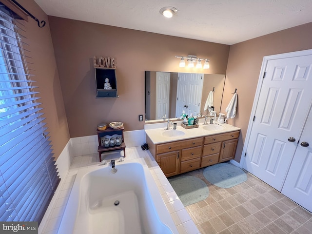 full bathroom with double vanity, a garden tub, and a sink