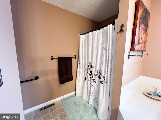 bathroom featuring a washtub, visible vents, a shower with shower curtain, baseboards, and tile patterned floors