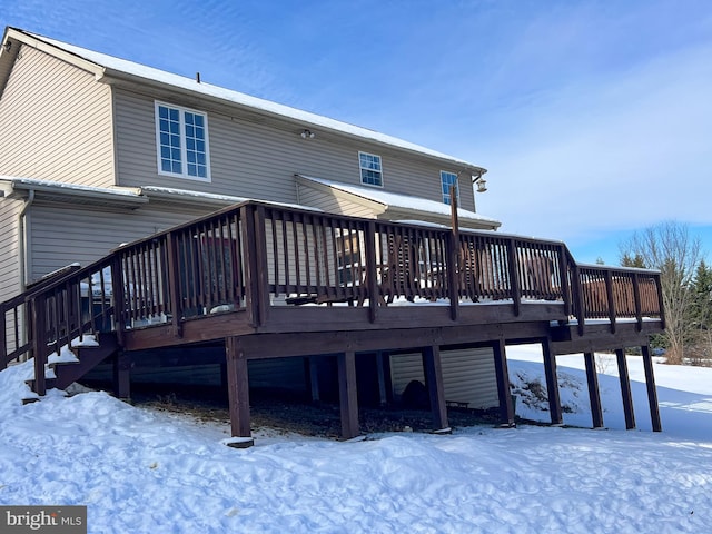 snow covered back of property with a wooden deck