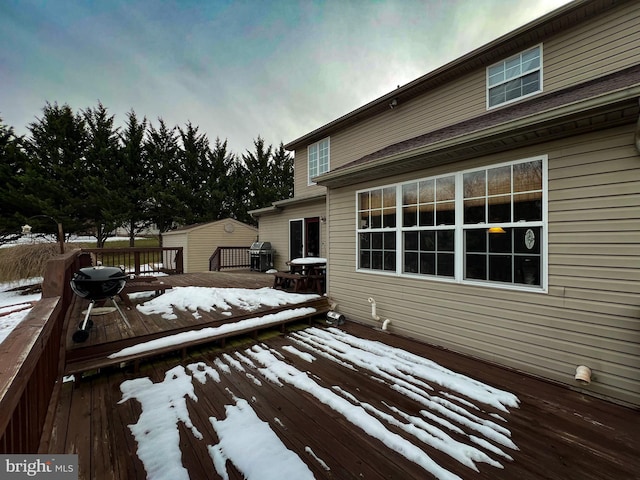 snow covered deck featuring a shed and an outdoor structure