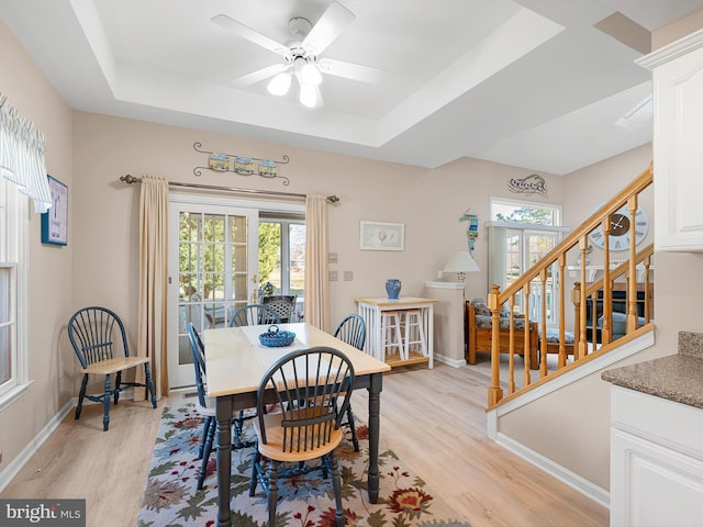 dining room featuring ceiling fan, plenty of natural light, a tray ceiling, and light hardwood / wood-style floors