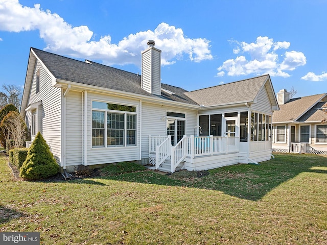 back of property with a yard, a deck, and a sunroom