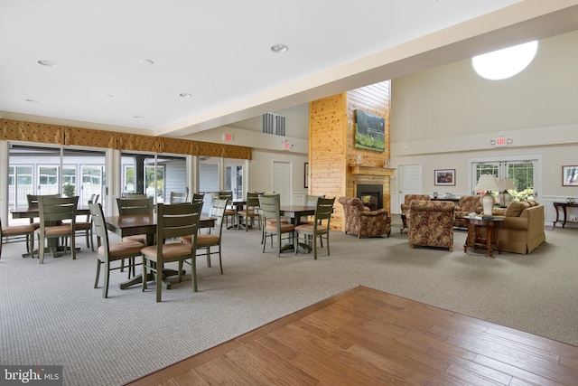 dining area with hardwood / wood-style floors, a fireplace, and a high ceiling