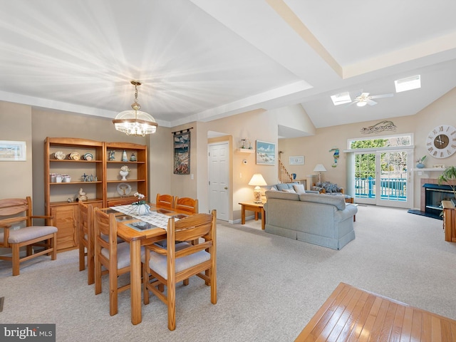 carpeted dining area with vaulted ceiling and ceiling fan with notable chandelier