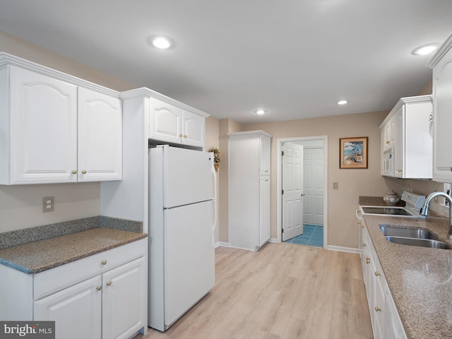 kitchen featuring light wood-type flooring, white appliances, sink, and white cabinets