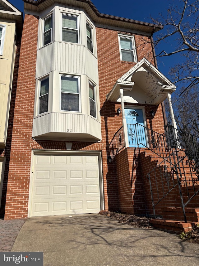 view of property with a garage, brick siding, and aphalt driveway