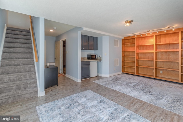 interior space featuring light wood-style floors, light countertops, stainless steel microwave, and visible vents