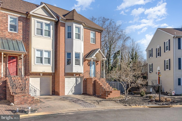 townhome / multi-family property featuring driveway, a garage, and brick siding