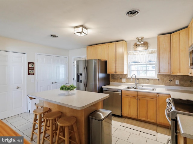 kitchen featuring stainless steel appliances, a center island, sink, and a kitchen bar