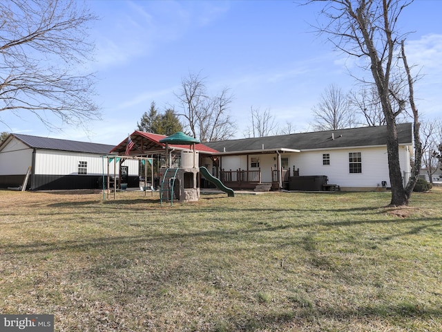 rear view of property with a playground and a lawn