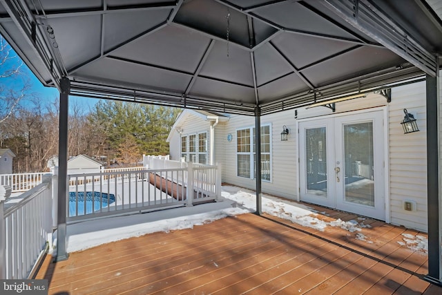 wooden terrace featuring fence, a fenced in pool, and french doors