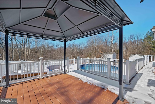 wooden terrace with a storage unit, fence, a fenced in pool, and an outdoor structure