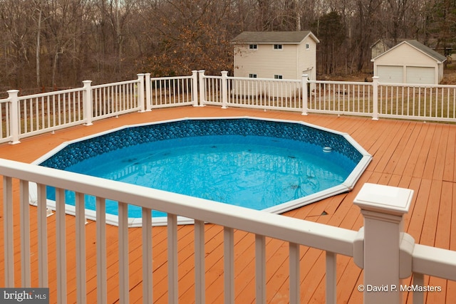 view of swimming pool featuring an outbuilding and a deck