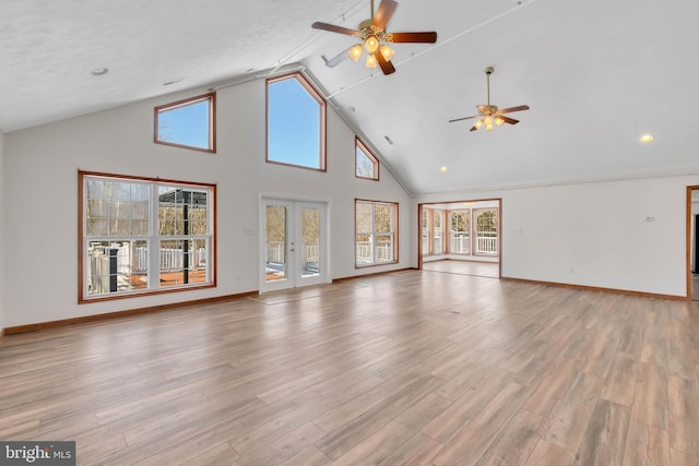 unfurnished living room with high vaulted ceiling, light hardwood / wood-style floors, french doors, and ceiling fan