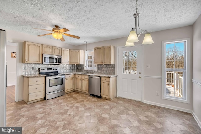 kitchen with visible vents, a sink, stainless steel appliances, light brown cabinets, and backsplash