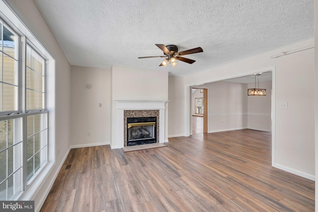 unfurnished living room featuring a ceiling fan, visible vents, wood finished floors, and a glass covered fireplace