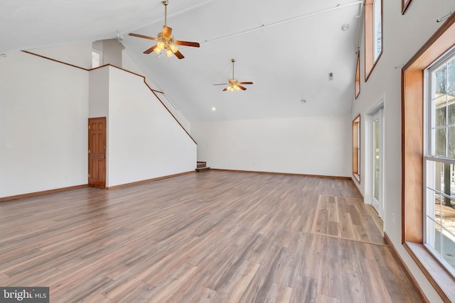 unfurnished living room featuring light wood-style floors, baseboards, high vaulted ceiling, and ceiling fan