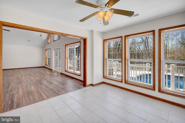 spare room with lofted ceiling, visible vents, a ceiling fan, baseboards, and tile patterned floors