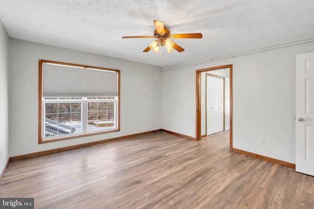 spare room with a ceiling fan, a textured ceiling, baseboards, and wood finished floors