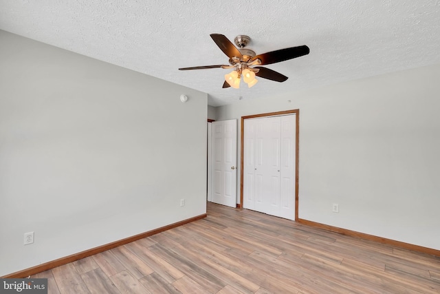 unfurnished room with light wood-style flooring, baseboards, and a textured ceiling