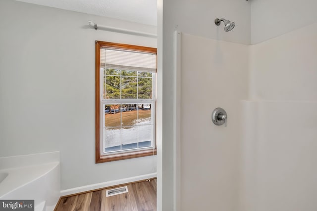 full bath with wood finished floors, walk in shower, visible vents, and baseboards