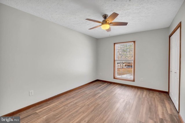 unfurnished bedroom with a closet, a textured ceiling, baseboards, and wood finished floors