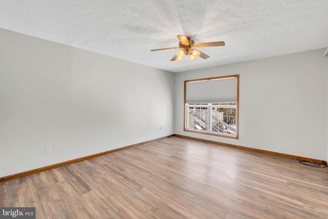 spare room featuring a ceiling fan, a textured ceiling, baseboards, and wood finished floors