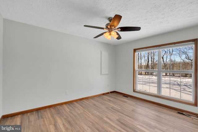 spare room featuring visible vents, ceiling fan, a textured ceiling, wood finished floors, and baseboards