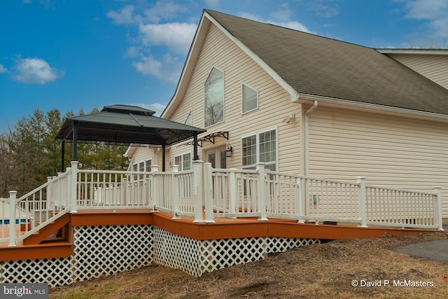 back of house featuring a shingled roof, a deck, and a gazebo