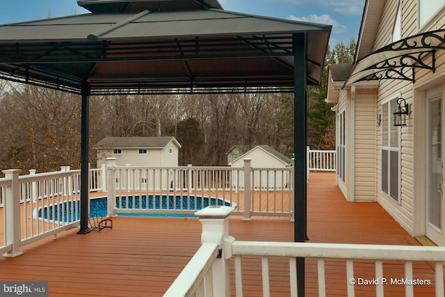 deck featuring a shed, a fenced in pool, and an outdoor structure