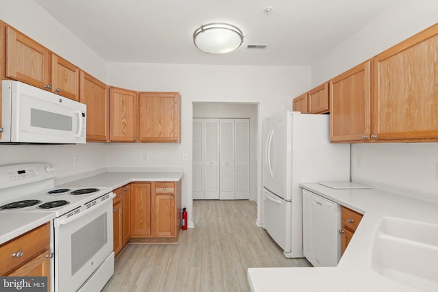 kitchen featuring white appliances, sink, and light hardwood / wood-style flooring