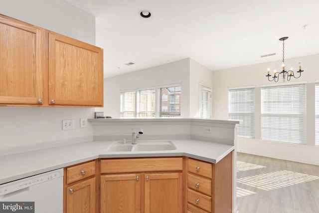 kitchen featuring pendant lighting, sink, an inviting chandelier, white dishwasher, and light hardwood / wood-style floors