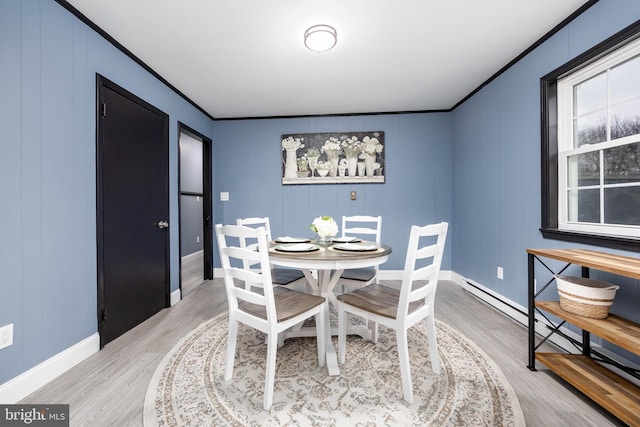 dining space featuring crown molding, baseboard heating, and hardwood / wood-style floors