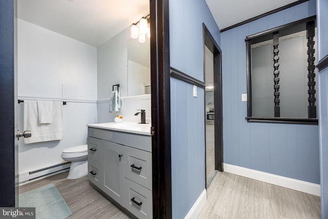 bathroom featuring vanity, a baseboard heating unit, wood-type flooring, and toilet