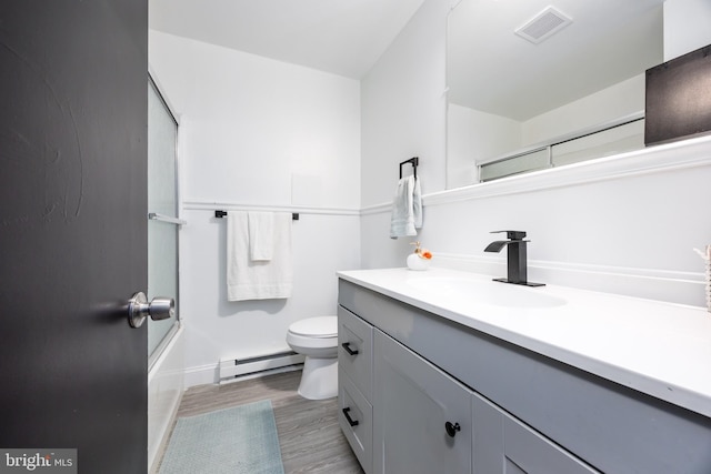 full bathroom featuring bath / shower combo with glass door, a baseboard radiator, wood-type flooring, vanity, and toilet