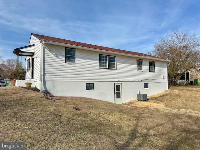 view of side of property featuring central AC unit and a lawn