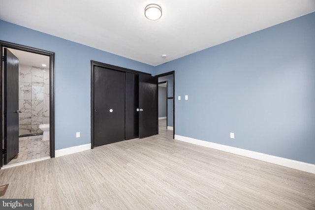 unfurnished bedroom featuring connected bathroom, a closet, and light wood-type flooring